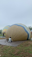 Colorful hot air balloons festival display distinct horizontal stripes are being inflated on the cloudy sky provide  backdrop. 