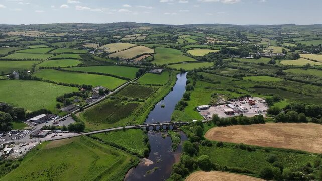 Clady Bridge, County Tyrone, Northern Ireland, June 2023. Drone panoramic high angle overview of arched bridge showcasing pasture fields sweeping out into the distance.