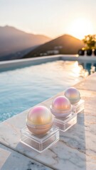 Three shimmering spherical cosmetic products displayed on a marble surface beside a tranquil swimming pool at sunset