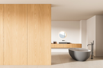 Modern minimalist bathroom interior with freestanding gray bathtub, wooden cabinets, and round...