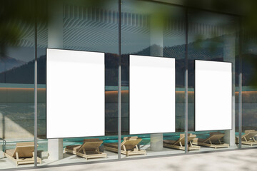 Three vertical blank poster mockups displayed on glass wall of modern building with minimalist...