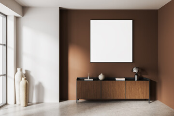 Framed empty poster mockup hanging on brown wall in modern minimalist interior with wooden cabinet,...