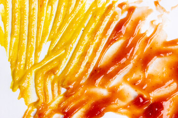 Close-up of mustard and ketchup smeared on a surface.