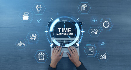 Time management concept with digital interface icons over laptop and hands typing on keyboard on blue wooden background.