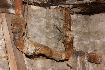 Rusty pipes with visible decay in an old basement.