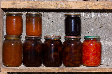 Assorted jars of preserves on a rustic wooden shelf.