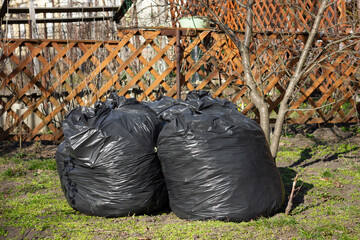 Three black garbage bags in a backyard.
