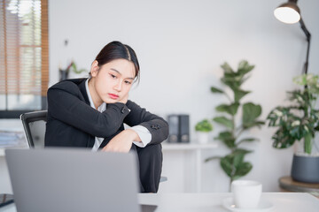 Young Asian businesswoman is experiencing stress and burnout from overwork while using laptop at...