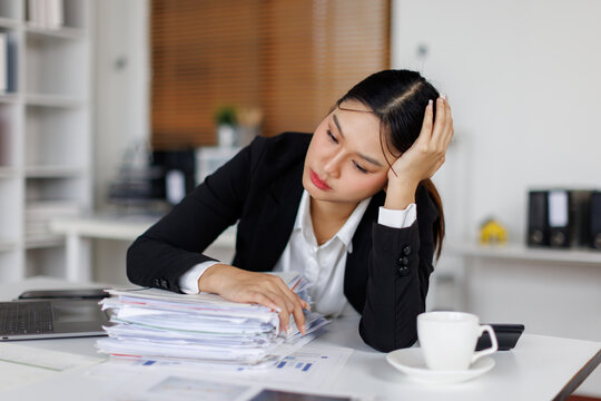 Tired and overworked young business asian woman falling to sleep while working late in her office