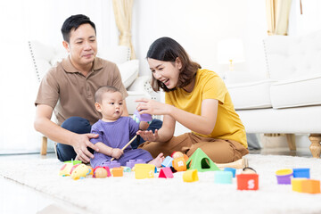Asian family mother,father ,son playing with colorful kid toys. Happy baby boy in kindergarten or...
