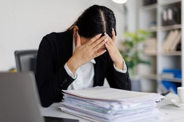 Stressed or sad and tired young business asian woman working with laptop at workplace.