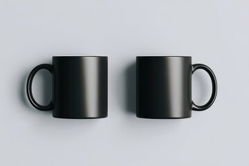 Two black mugs, side-by-side, on a light gray surface