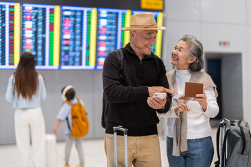 Senior asian couple with luggage checking passport planning trip showing travel preparation at...