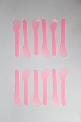 Several pink plastic disposable cosmetic spatulas for wax depilation or sugaring on white background. Beauty procedures, skin care