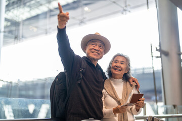 Senior asian couple with luggage checking passport planning trip showing travel preparation at...