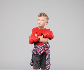 Little boy with boxing gloves on gray background