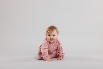 Cute little baby crawling on light grey background