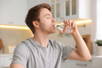 Man drinking water from glass in kitchen