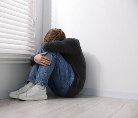 Scared man suffering from paranoia near window indoors