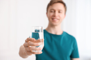 Man with glass of water at home, selective focus