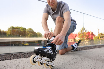 Man putting on roller skates outdoors, closeup