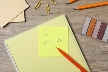 Paper note with phrase Join Us and stationery on wooden table, flat lay