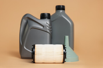Motor oil in plastic canisters, filter and funnel on beige background