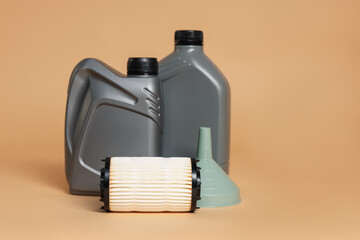 Motor oil in plastic canisters, filter and funnel on beige background, space for text