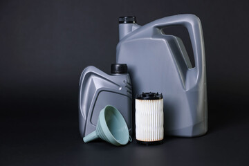 Motor oil in plastic canisters, filter and funnel on black background, space for text