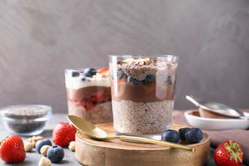 Delicious chocolate pudding with chia seeds, berries and hazelnuts in glasses on table, closeup