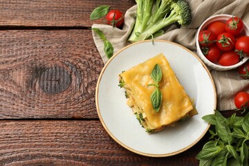 Piece of tasty vegetarian lasagna and ingredients on wooden table, flat lay. Space for text