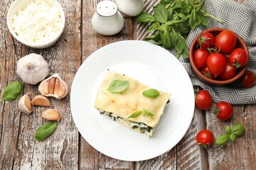 Piece of tasty vegetarian lasagna and ingredients on wooden table, flat lay