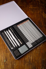 Metal box of art supplies. Set of graphite pencils, rubber, knife and kneaded eraser. Holder handle...