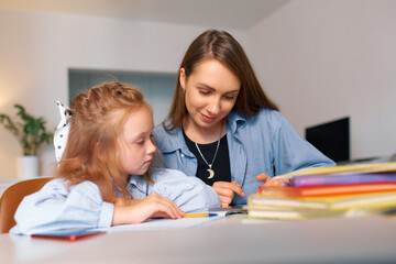 Young mother and daughter doing homework for elementary school