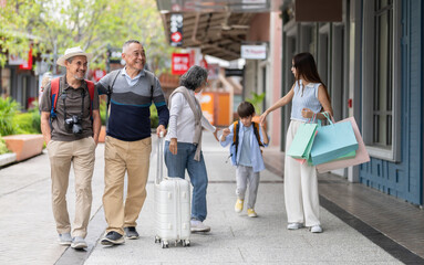 Fototapeta premium Multigenerational family walking travel and shopping in shopping street, happy grandparents parents and child enjoy vacation together with backpack retail with shopping bags showing family leisure