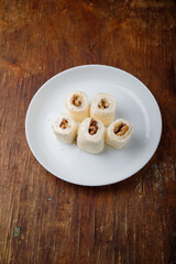 Turkish delight, white locum roll with walnut and coconut flakes on white plate, wooden background. Eastern sweets, oriental food. Traditional tasty dessert. Copy space. Top view