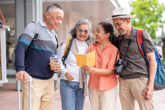 Senior asian tourism travel group reading guidebook together with smiles, enjoy retirement, friendly active aging tourism, senior health and wellness, retirement life insurance and vacation planning