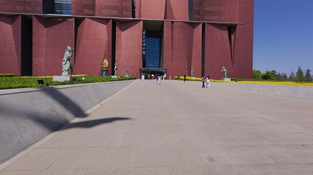 The exterior of the Yunnan Provincial Museum features geometric red-brown architecture, large banners, and trees in bloom&mdash;capturing modern cultural dignity and the vibrant presence of an urban heritag