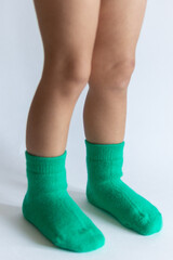 Legs of a 2 year old baby in warm green socks on a white background