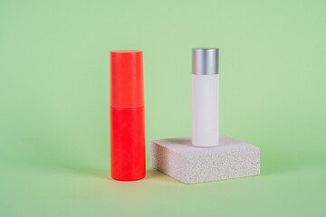 White tube and red spray on light white podiums. White blank unbranded flacons with cosmetology products. Professional concept of skin care on green background.