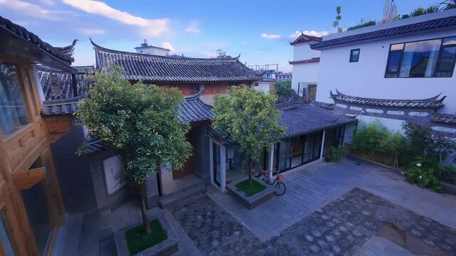 A peaceful courtyard in Lijiang features tiled roofs, carved wooden windows, and stone paths&mdash;capturing the traditional charm and tranquil rhythm of ethnic residential architecture in Yunnan.