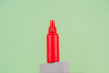 Cosmetic red bottle. Womens cosmetic accessory for makeup with stylish props on green background.
