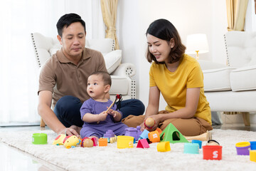 Asian family mother,father ,son playing with colorful kid toys. Happy baby boy in kindergarten or...