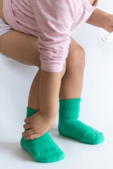 Legs of a 2 year old baby in warm green socks on a white background
