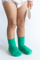Legs of a 2 year old baby in warm green socks on a white background