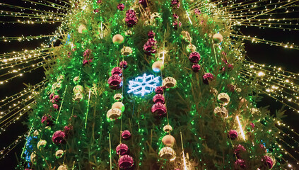Bright green Christmas tree adorned with colorful ornaments and sparkling lights during holiday celebrations at night