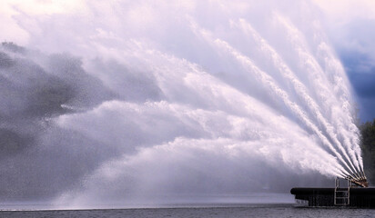 Water jets create stunning display over serene lake at sunset during a summer event
