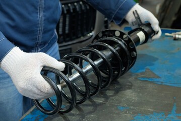 Maintenance at a car service station.Replacement of the shock absorber strut.An auto mechanic...