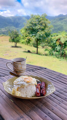 Filipino breakfast meal with rice, sausage, and fried egg served with coffee on a table overlooking a lush mountain landscape showing the calm of rural living