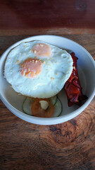 Overhead view of a bowl of sunny-side-up eggs, rice, and hot dog which is a typical local Filipino breakfast meal and comfort food